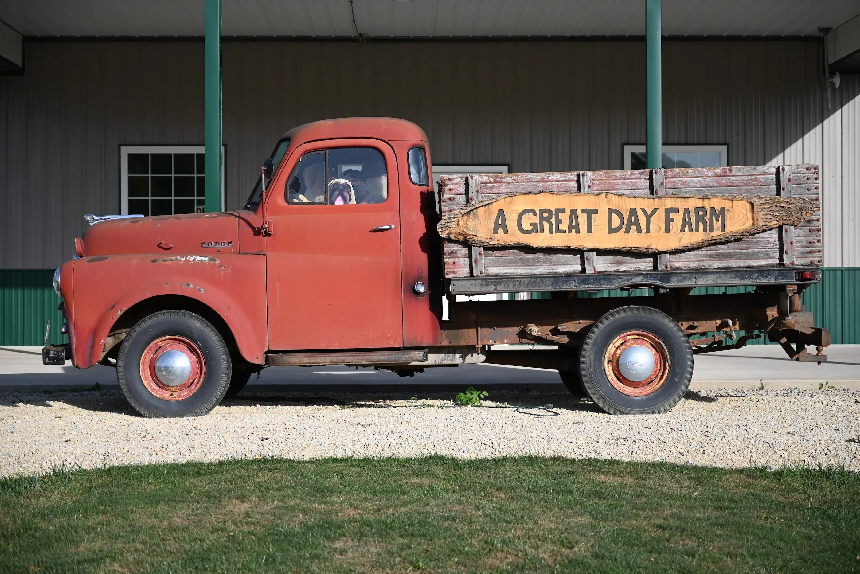 Old red truck parked in front of a great day farm pole barn